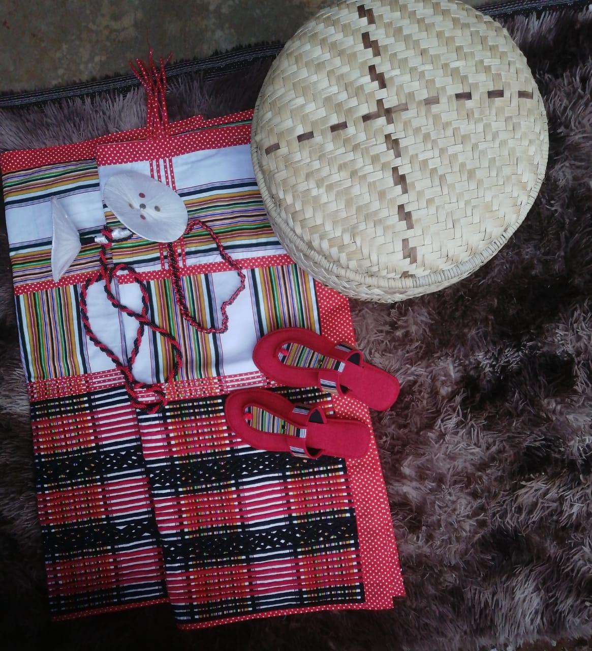 A traditional Venda Minwenda outfit laid out with a patterned fabric and accessories including a woven hat and shoes.