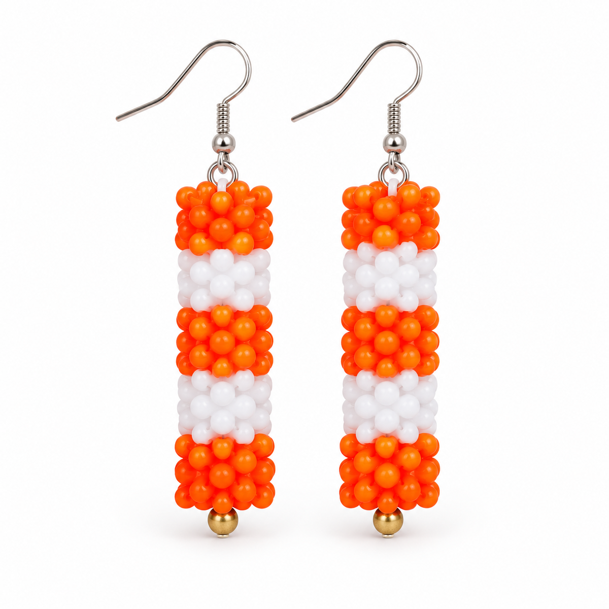 Long Orange & White plastic snowflake bead earrings on white background